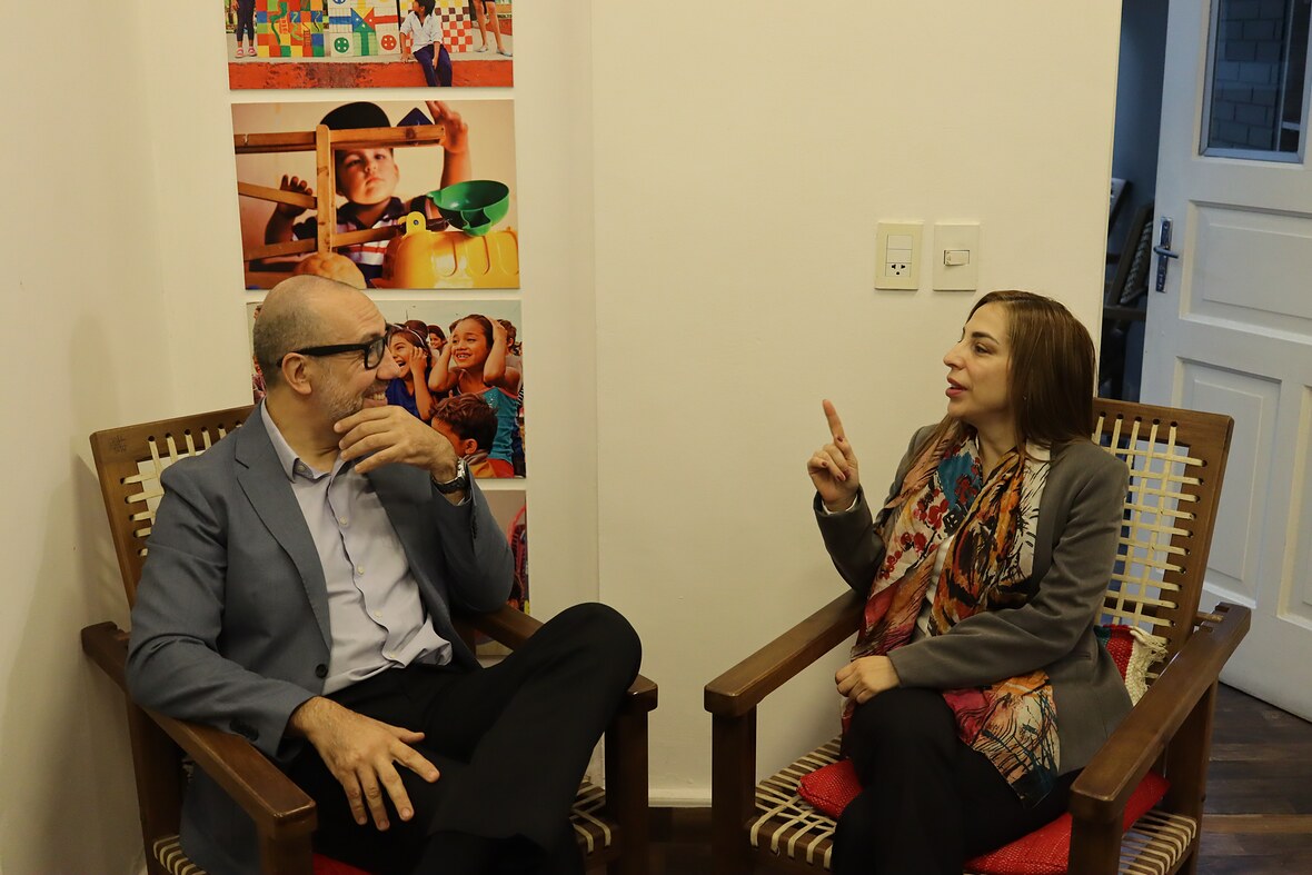 Dos integrantes de INDEX conversan sentados en sillones de madera en la sede